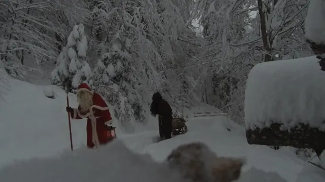 Samichlaus mit Laterne und Schmutzli mit Schlitten im tief verschneiten Wald